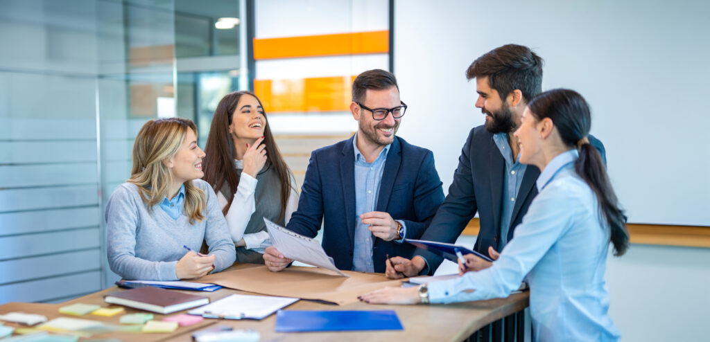 Entrepreneurs engaging in business discussions, collaboratively seeking solutions. Group of professionals converses while gathered at office desk.